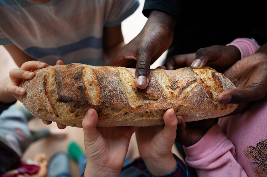 Children of various races holding a loaf of bread in a conceptual image.
